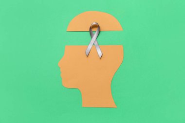 Yeşil arka planda gri farkındalık kurdelesi olan kağıt insan kafası