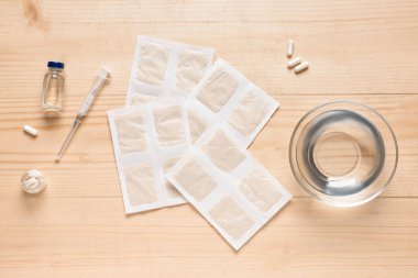 İlaçlı hardal alçıları ve ahşap arka planda bir kase su.