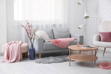 İçinde kanepe, sehpa ve vazoda açan bahar çiçekleri olan oturma odası.