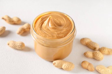 Beyaz arka planda fındıklı fıstık ezmesi kavanozu