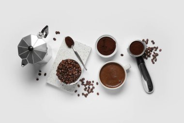 Beyaz arka planda fincanlı gayzer kahve makinesi, portafilter ve fasulye.