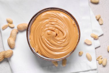 Beyaz arka planda fındıklı bir kase fıstık ezmesi