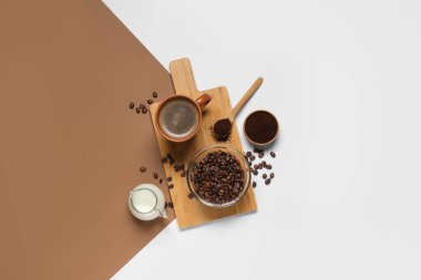 Bir fincan lezzetli kahve, sütlü sürahi, pudra ve fasulye renkli arka planda.