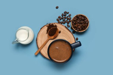 Mavi arka planda bir sürahi sütlü ve fasulyeli kahve.