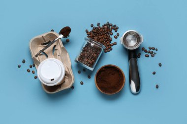 Kahve çekirdekleri, pudra ve mavi arka planda iskele filtresi olan paket kâğıdı bardağı.