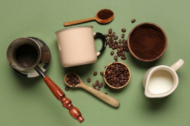 Yeşil arka planda fincan, kahve çekirdeği, toz ve sütle cezalandırıldık.