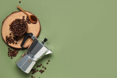 Gayzer kahve makinesi ve yeşil arka planda fasulye kasesi.
