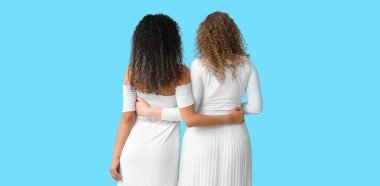 Açık mavi arka planda sarılan genç kadınlar