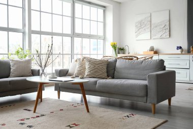 Interior of modern kitchen with grey sofas, dining table and counters