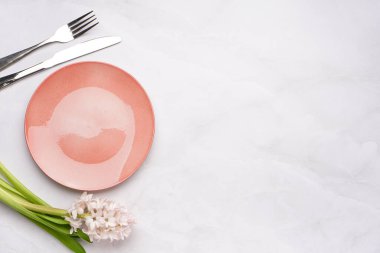 Temiz tabak, çatal bıçak takımı ve beyaz arka planda güzel sümbül çiçeği.