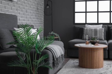 Modern oturma odasının içinde rahat koltuklar, kanepe ve kahve masasının üzerinde floraryum var.