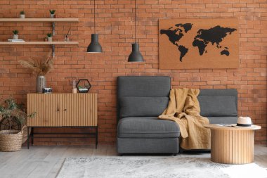 Tuğla duvarın yanında rahat koltukları ve sehpası olan şık bir oturma odası.