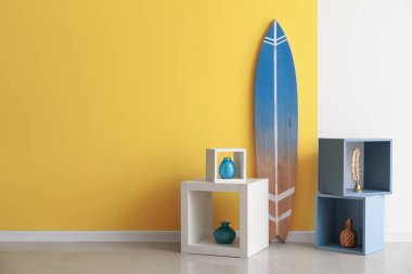 Renkli duvarın yanında rafları olan sörf tahtası.