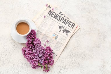 Gazeteli güzel leylak çiçekleri ve açık grunge arka planda bir fincan kahve.