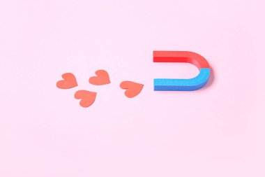 Magnet with paper hearts on pink background. Love concept clipart