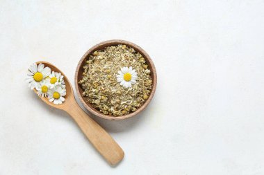 Açık arkaplanda bir kase kurumuş ve taze papatya çiçeği.