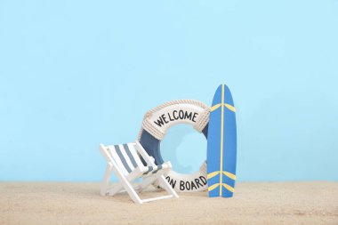 Minyatür sörf tahtası, şamandırası ve mavi arka planda kum üzerinde yaşam şamandırası olan yaratıcı kompozisyon