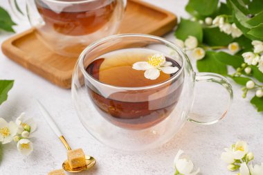 Bir bardak çay ve arka planda güzel yasemin çiçekleri, yakın plan.