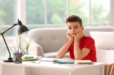 Küçük çocuk evde ders alıyor.