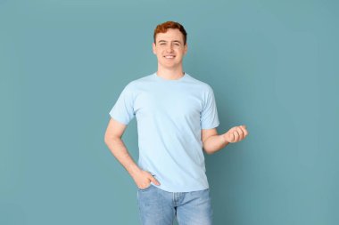 Mavi arka planda tişörtlü genç adam.