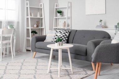 Rahat koltuğu ve gri kanepesi olan aydınlık oturma odasının içinde.