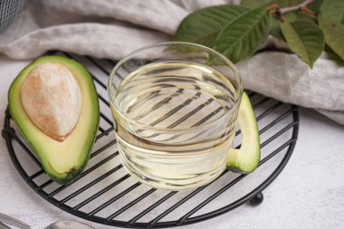 Taze olgun avokado ve beyaz zemin üzerinde cam kase gerekli yağ ile şebeke