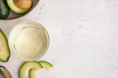 Beyaz arka planda avokado dilimli cam kase.