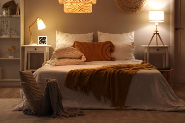 Rahat yatak odası, battaniye ve geceleri parlayan lambalar.