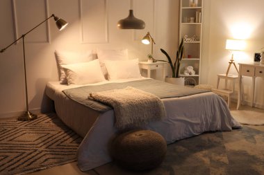 Rahat yatağın üzerinde yumuşak battaniyeler ve geceleri parlayan lambalar olan rahat yatak odasının içi.