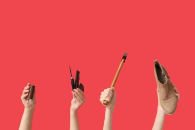 Kırmızı arka planda ayakkabı, çekiç ve el işi aletleri olan kadın eller. Ayakkabı tamir konsepti