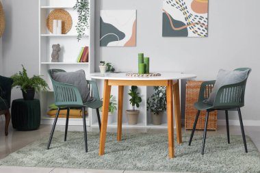 Sandalyeleri, masası ve rafları olan modern oturma odası.