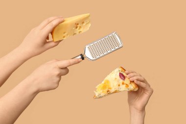 Birçok el bej arka planda pizza dilimi, rende ve peynir tutuyor.