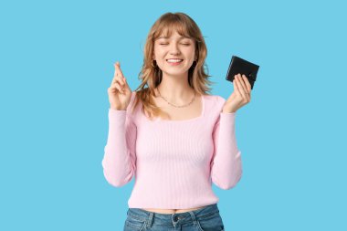 Güzel genç bir kadın mavi arka planda siyah cüzdan taşıyor.