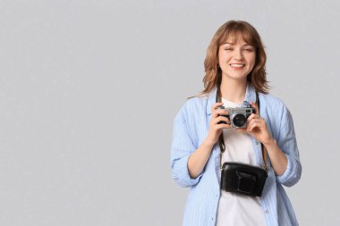 Beyaz arka planda kamera ve çanta olan güzel genç bir kadın.