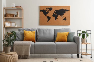 Gri kanepeli, dünya haritalı, yastıklı ve çiçekli güzel bir oturma odası.