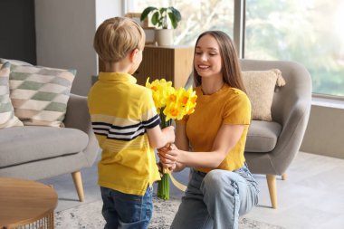 Son greeting his happy mother with bouquet of beautiful narcissus at home