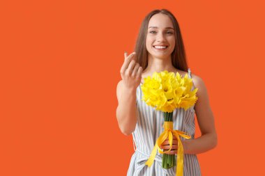 Beautiful young happy woman with bouquet of beautiful narcissus on orange background