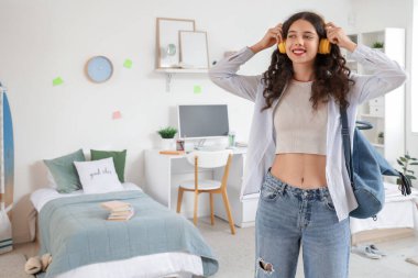 Yurt odasında kulaklıklı ve sırt çantalı bir kız öğrenci.