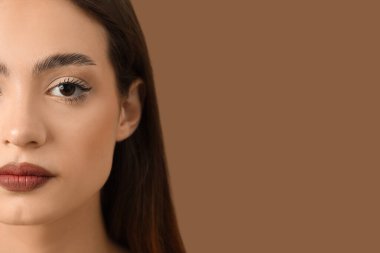 Young woman with beautiful eyebrows on brown background, closeup clipart