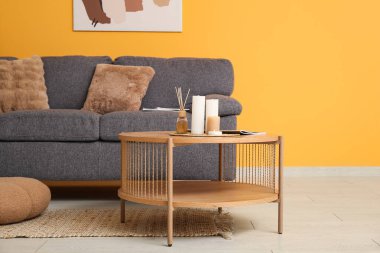 Odasında yanan mumlar, dergi ve renkli duvarın yanındaki rahat kanepe olan ahşap masa.