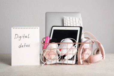 Metin DIGITAL DETOX ve ışık arkaplan üzerinde modern cihazlarla dolu bir sepet içeren defter