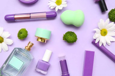 Bir şişe parfüm, oje, makyaj malzemeleri ve leylak arkaplanda çiçekler.