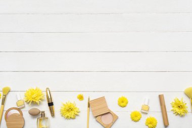 Beyaz ahşap arka planda makyaj ürünleri, aksesuarlar ve çiçeklerle kompozisyon