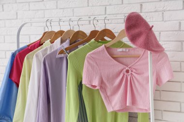 Beyaz tuğlalı duvarın yanında renkli giysiler ve bereyle dizilin. Yakın çekim.