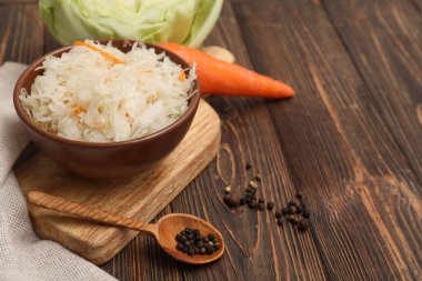 Ahşap arka planda malzemelerle dolu kasede lezzetli lahana turşusu. Yakın çekim.