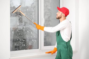 Odada cam sileceği olan bir erkek işçi.
