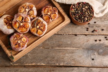 Fırında sarımsak, biberiye, karabiber ve ahşap zemin üzerinde kekik olan bir tahta.