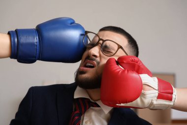 Ofiste genç işadamının yüzüne boks eldiveniyle vurulması, yakın plan. Nakavt konsepti