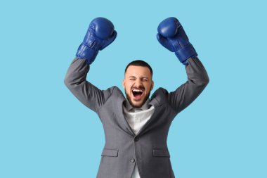 Mavi arka planda boks eldivenleri olan kızgın bir iş adamı. Nakavt konsepti