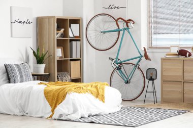 Yatağı, bisikleti ve raf ünitesi olan bir gencin odası.